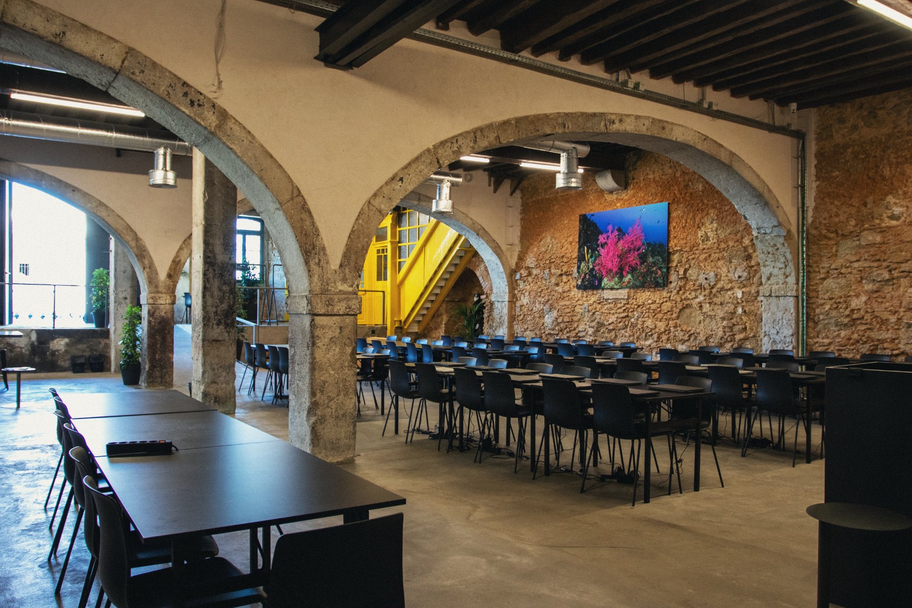 O espaço da Shaken Academy, piso 0 — arcos de pedra e escadaria amarela